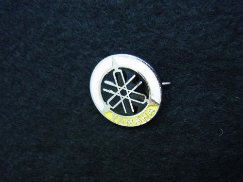 A vintage enamel pin badge: "yamaha" tuning fork